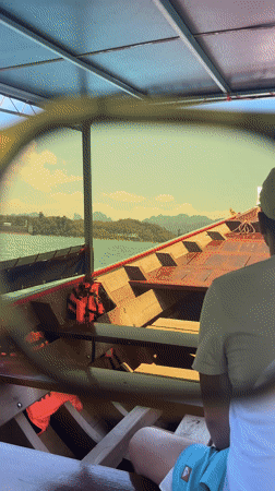 Tourist films longtail boat cruise on Thai lake