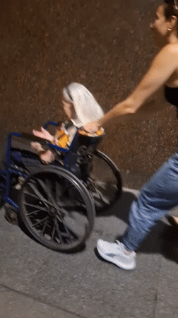 Woman pushes elderly person in wheelchair through Buenos Aires