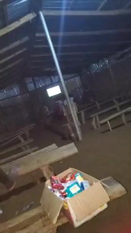 This video shows a screen displaying a soccer game. The screen is illuminated with a bright white light. The background is dark, making it difficult to discern any specific details. There are some indistinct shapes visible, possibly people or furniture, but they are too blurry to identify. The overall impression is of a dimly lit room with a television screen as the focal point.