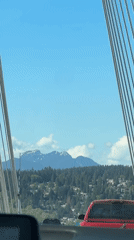 Vehicle crosses cable-stayed bridge in Coquitlam under clear skies