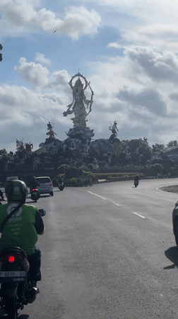 Motorcycle rider navigates busy Denpasar roundabout during morning commute