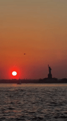 Vibrant sunset captured over New York Harbor with Statue of Liberty