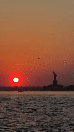 Vibrant sunset captured over New York Harbor with Statue of Liberty