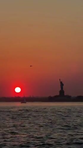 Vibrant sunset captured over New York Harbor with Statue of Liberty