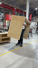 Worker lifts wooden cube in Mexican industrial workshop