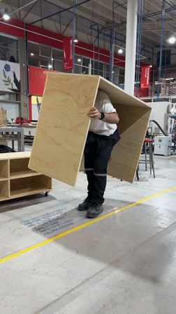 Worker lifts wooden cube in Mexican industrial workshop