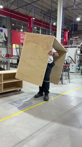 Worker lifts wooden cube in Mexican industrial workshop