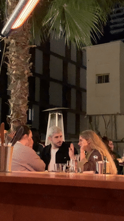 Three people gather at outdoor table in Tel Aviv