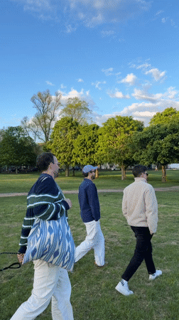 Three men walk across sunny London park field