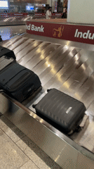 Passengers collect luggage at Mumbai airport baggage carousel