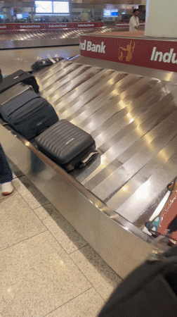 Passengers collect luggage at Mumbai airport baggage carousel