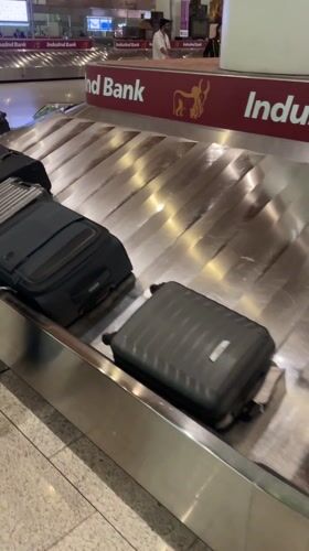 Passengers collect luggage at Mumbai airport baggage carousel