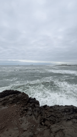 Overcast evening captured along Arica's rocky coastline with ships offshore