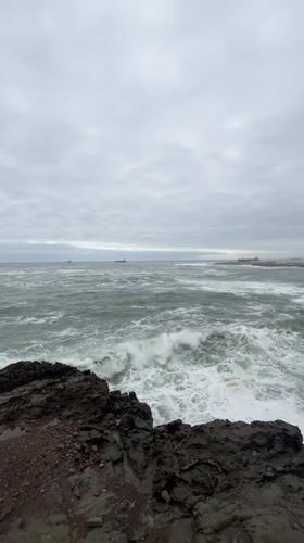 Overcast evening captured along Arica's rocky coastline with ships offshore