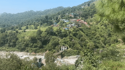 Lush Palampur valley with river, hillside homes, and green hills