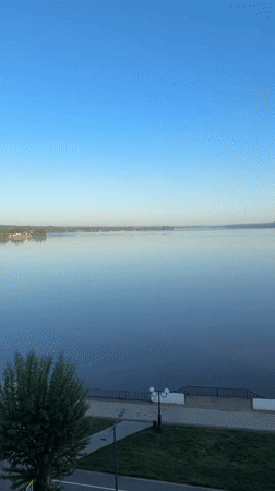 Man in swim trunks carries blue object near Votkinsk waterfront