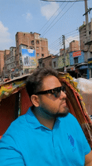 Man in blue polo rides rickshaw through busy Dhaka streets