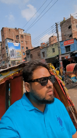 Man in blue polo rides rickshaw through busy Dhaka streets