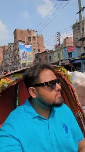 Man in blue polo rides rickshaw through busy Dhaka streets