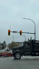 Black dump truck crosses wet intersection in New Westminster