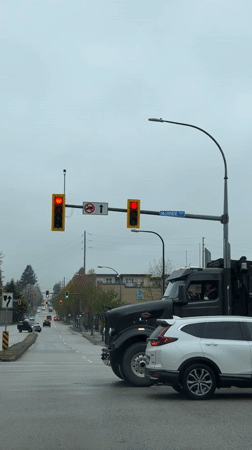 Black dump truck crosses wet intersection in New Westminster