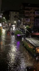 Heavy rain floods urban street as cars drive through at night