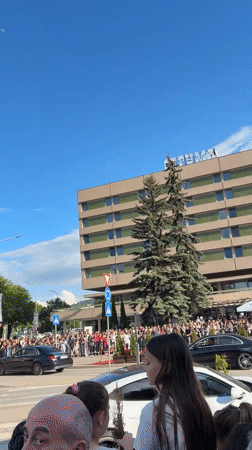 Crowd gathers behind barricades in Pernik to observe passing vehicle