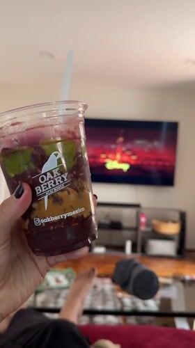 Person enjoys layered smoothie while relaxing on couch in Mexico City