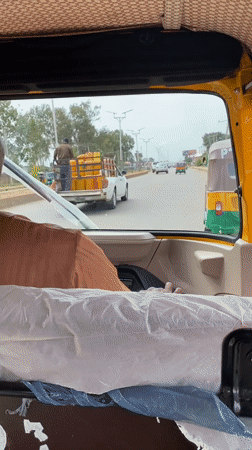 Pickup truck transports yellow containers through Bukuru, Nigeria streets