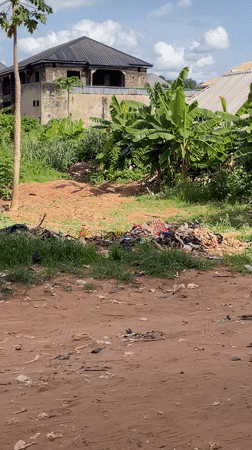 Person carries textiles on head along dirt road in Nkpor