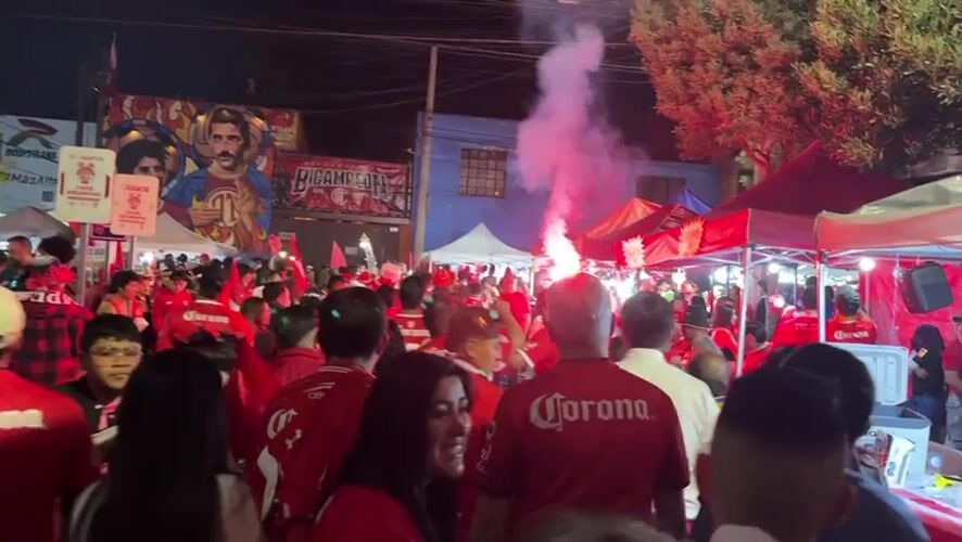 Corona-shirted crowd gathers with tents, flares in Toluca street