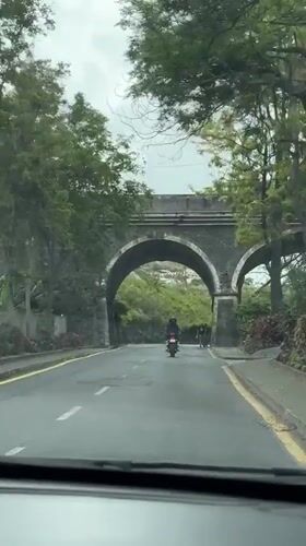 Vehicles pass through stone archway in Funchal