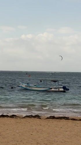 Kite surfers and traditional boats off a Denpasar beach