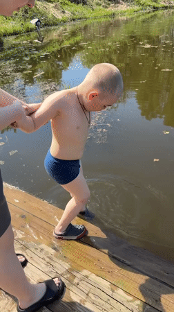Child prepares for swim with adult supervision in Zhigalki