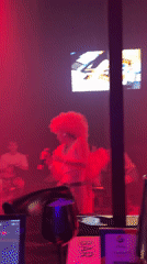 Woman performs in red wig at bar stage