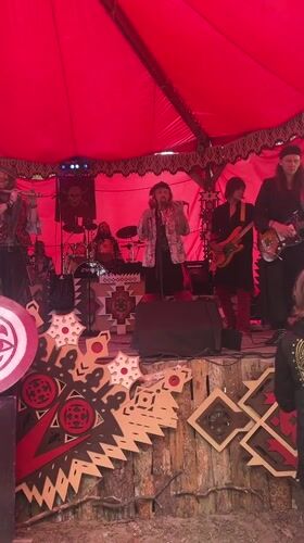 Live band performs under red tent on decorated outdoor stage