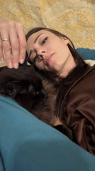 Woman pets black cat on bed in Saint Petersburg