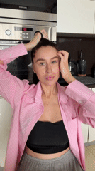 Woman fixes hair, drinks coffee in Khimki kitchen