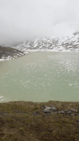 Red train journeys through rainy Swiss Alps near Pontresina