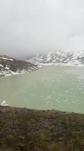 Red train journeys through rainy Swiss Alps near Pontresina