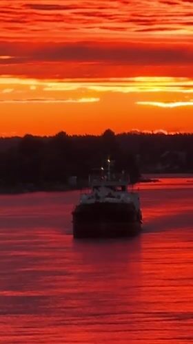 Fiery sunset over the Svir River with a barge passing through