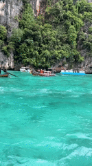 Longtail boats and swimmers among Ao Nang's karst cliffs