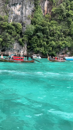 Longtail boats and swimmers among Ao Nang's karst cliffs