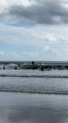 Surfers gather at Kuta Beach during overcast morning