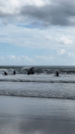 Surfers gather at Kuta Beach during overcast morning