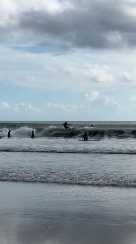 Surfers gather at Kuta Beach during overcast morning