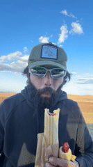 Man eats hot dogs outdoors in Первомайское, Russia
