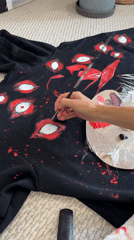 Artist paints detailed eyes on black sweatshirt in Krasnoyarsk
