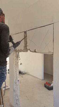 Construction worker demolishes interior wall in Bat Yam building