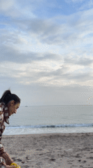 Woman plays fetch with poodle on Montenegro beach